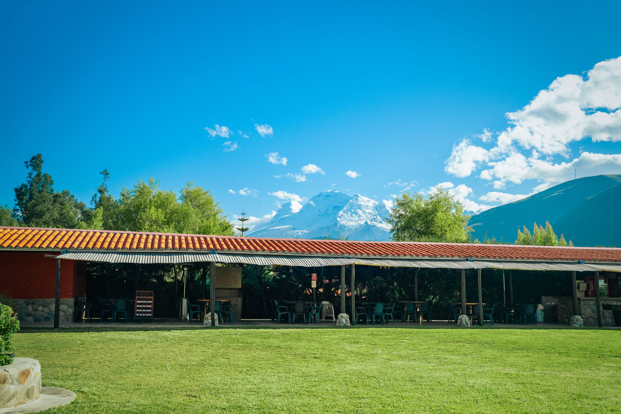 Recreo turístico Anta con mesas y sillas, y montañas de fondo en un día nublado.
